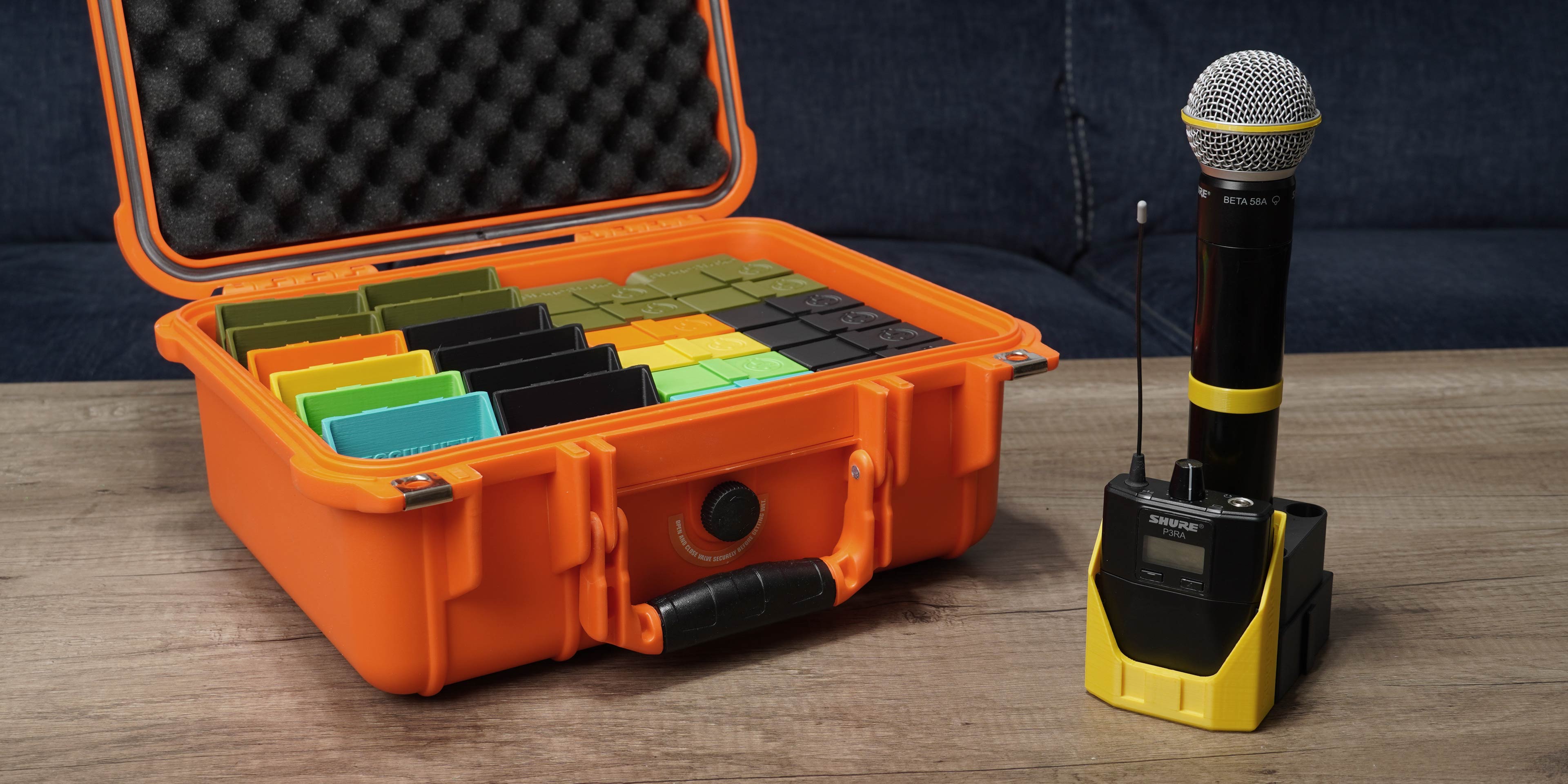 Picture of an orange plastic carrying case containing twelve wireless pack holders and twelve wireless handheld bases